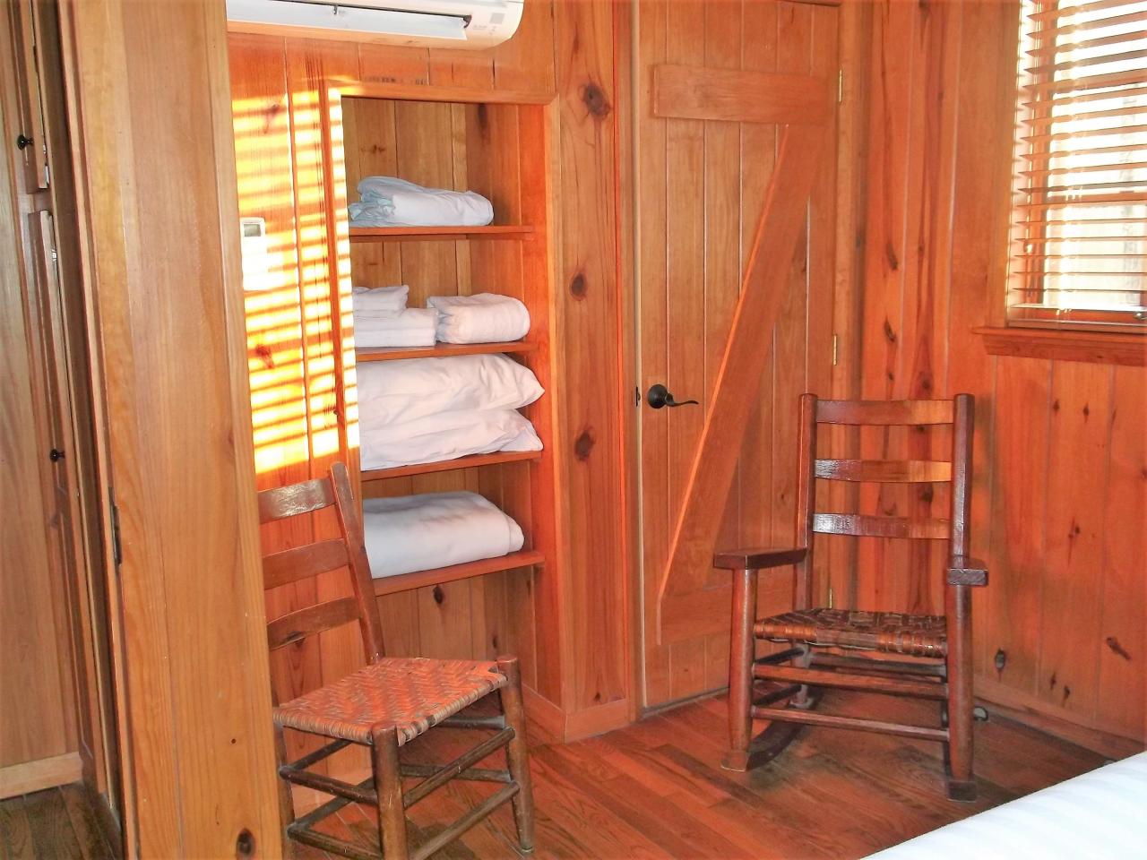 A view of the seating area in the bedroom with 2 rocking chairs in front of the shelves storing the linens